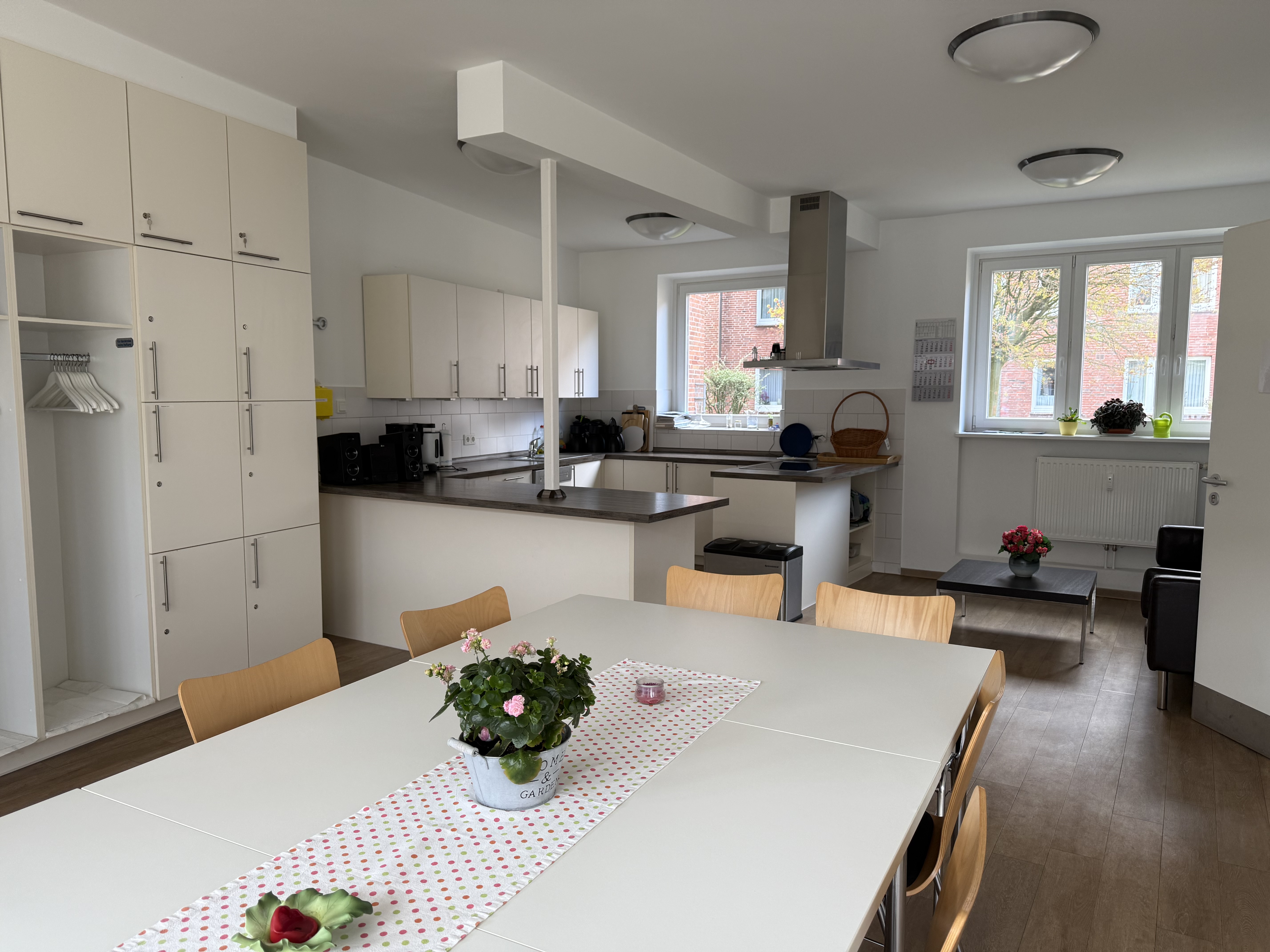 Innenraum Nachbarschaftstreff mit Esstisch und Stühlen im Vordergrund und Küche im Hintergrund